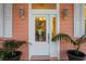 Close-up of front door featuring sidelights, stylish lighting fixtures, and potted plants at 3431 Riderwood Dr, Dade City, FL 33523