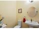 Cozy powder room with pedestal sink, round mirror, and decorative accents offering practical elegance at 3431 Riderwood Dr, Dade City, FL 33523