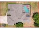 Aerial shot shows the house with a screened-in pool, a spacious roof and its surrounding landscape at 3464 Misty View Dr, Spring Hill, FL 34609