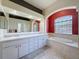 Bathroom featuring dual sinks, a large soaking tub, and travertine tile work at 3464 Misty View Dr, Spring Hill, FL 34609