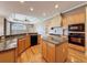 Well-lit kitchen featuring an island, wooden cabinets, granite countertops, and modern appliances at 3464 Misty View Dr, Spring Hill, FL 34609