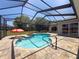 Sparkling pool within screened enclosure, featuring an umbrella table and paved patio at 3464 Misty View Dr, Spring Hill, FL 34609