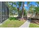 Spacious backyard with a screened-in pool enclosure and a stepping stone pathway leading to a charming outbuilding at 520 Lafayette Blvd, Oldsmar, FL 34677
