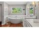 Bright bathroom features a soaking tub beneath a window and dual sinks with beautiful lighting at 520 Lafayette Blvd, Oldsmar, FL 34677
