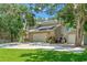 Landscaped front lawn leads to an updated home with brick accents and attached garage, nestled beneath mature trees at 520 Lafayette Blvd, Oldsmar, FL 34677