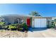 Charming single-story home featuring a red front door, attached garage and lovely garden in front of the home at 5316 Drift Tide Dr, New Port Richey, FL 34652