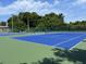 Community tennis courts with green and blue surface, surrounded by trees and green fencing at 6410 Spring Flower Dr # 26, New Port Richey, FL 34653