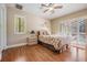Cozy bedroom with hardwood floors, ceiling fan, and natural light from the windows at 663 Turnberry Ct, Tarpon Springs, FL 34688