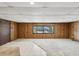Finished basement area featuring neutral carpet, tile, wood paneling and a window at 7012 Ponderosa Dr, Tampa, FL 33637