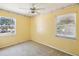 A cheerful yellow bedroom with a ceiling fan and a large window at 7012 Ponderosa Dr, Tampa, FL 33637