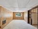 A spacious living room with wood paneling, soft carpet, and a large window overlooking the front yard at 7012 Ponderosa Dr, Tampa, FL 33637