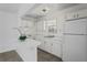 The kitchen has white cabinets and appliances, a breakfast bar, and a sunny window overlooking the sink at 7050 Merrick Ln, Spring Hill, FL 34606