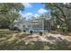 The house is surrounded by mature trees and landscaping, featuring a screened-in swimming pool at 7233 Royal Oak Dr, Spring Hill, FL 34607