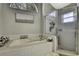 Bright bathroom featuring a tiled tub, glass shower, and decorative window at 7233 Royal Oak Dr, Spring Hill, FL 34607