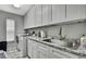 A bright laundry room with stainless steel sink, granite counters, and white cabinets at 7233 Royal Oak Dr, Spring Hill, FL 34607