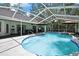 A screened-in in-ground swimming pool and patio area includes two umbrellas for shade at 7233 Royal Oak Dr, Spring Hill, FL 34607