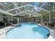 Screened-in swimming pool and hot tub with lounge chairs, umbrellas, and furniture under the screen at 7233 Royal Oak Dr, Spring Hill, FL 34607