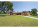 Charming home with lush lawn, long driveway, and inviting curb appeal under a clear blue sky at 7270 Nightwalker Rd, Weeki Wachee, FL 34613
