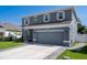 Well-maintained two-story home with a gray facade, complemented by lush landscaping and a two-car garage at 733 Old Windsor Way, Spring Hill, FL 34609