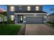 Charming two-story home with a well-manicured lawn, lush greenery, and a gray two-car garage at 733 Old Windsor Way, Spring Hill, FL 34609