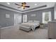 Cozy main bedroom with neutral colored walls, tray ceiling, ceiling fan, and ensuite bath at 733 Old Windsor Way, Spring Hill, FL 34609