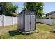 Outdoor backyard storage shed with double doors and windows situated inside a white fence at 733 Old Windsor Way, Spring Hill, FL 34609