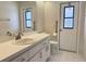 Bathroom with white vanity, toilet, and door with window and grab bar at 7538 Landmark Dr, Spring Hill, FL 34606
