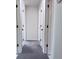 Hallway with carpet flooring, white trim, and multiple closet doors at 7538 Landmark Dr, Spring Hill, FL 34606