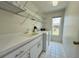 Laundry room features a utility sink, washer, dryer, shelving, and bright window at 7538 Landmark Dr, Spring Hill, FL 34606