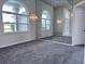 Neutral carpeted living room with decorative lighting, windows, and access to other living areas at 7538 Landmark Dr, Spring Hill, FL 34606