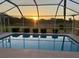 Screened-in pool offers a serene view with lush landscaping and a beautiful sunset backdrop at 7538 Landmark Dr, Spring Hill, FL 34606