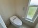 Close-up of modern toilet with remote control and window view in a bright bathroom at 7538 Landmark Dr, Spring Hill, FL 34606
