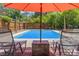Relaxing backyard pool area with lounge chairs, wood privacy fence, and shade umbrella at 800 N Walton Ave, Tarpon Springs, FL 34689