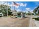 View of the gated entrance featuring an American flag, guard house, and lush landscaping at 8210 Aquila St # 218, Port Richey, FL 34668