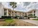 A condo building with balconies and a covered drive-through showcases tropical landscaping and a bright, sunny ambiance at 8210 Aquila St # 218, Port Richey, FL 34668