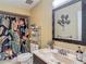 Well-lit bathroom features a sink, mirror, tropical-themed shower curtain, and decorative storage at 8600 N Briar Patch Dr, Port Richey, FL 34668