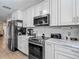 Kitchen with white cabinets, black appliances, and marble countertops, great for cooking and entertaining at 8600 N Briar Patch Dr, Port Richey, FL 34668