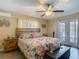Bright main bedroom with a ceiling fan, French doors, and wood-look flooring, perfect for relaxation at 8600 N Briar Patch Dr, Port Richey, FL 34668