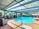 Gorgeous screened in pool area with a blue in-ground pool, chairs, bar, and dining set at 8600 N Briar Patch Dr, Port Richey, FL 34668
