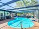 Beautiful screened in pool area with a blue in-ground pool, bar, chairs, and dining set at 8600 N Briar Patch Dr, Port Richey, FL 34668