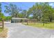 Exterior view of a home with a long driveway, wooden fence, and mature trees at 9226 Dan Lynn St, Brooksville, FL 34601