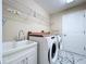 Neat laundry room with utility sink, modern washer/dryer, and storage shelves at 1006 Sweet Jasmine Dr, Trinity, FL 34655