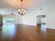 Open living room with hardwood floors, a decorative chandelier, and access to a screened-in lanai for indoor/outdoor living at 1006 Sweet Jasmine Dr, Trinity, FL 34655