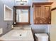 Comfortable bathroom featuring wood cabinets, a granite countertop, and framed mirror at 10228 Beechcraft St, New Port Richey, FL 34654