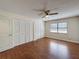 Bedroom with hardwood floors, a ceiling fan, a window with blinds, and large closets at 10228 Beechcraft St, New Port Richey, FL 34654