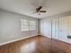 Bedroom with hardwood floors, a ceiling fan, a window, and two closets, offering a comfortable and functional space at 10228 Beechcraft St, New Port Richey, FL 34654