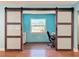 View of the bright office area with barn doors, built-in desk, and window overlooking the yard at 10228 Beechcraft St, New Port Richey, FL 34654