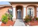 Inviting front entrance featuring a charming walkway, manicured landscaping, and stylish architectural columns at 12040 Penzance Ln, New Port Richey, FL 34654