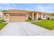Charming single-story home with manicured lawn, beige exterior, and a two car garage at 12040 Penzance Ln, New Port Richey, FL 34654