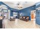 Comfortable living room with blue walls, tile flooring, ceiling fan, and sliding glass doors to the pool at 12040 Penzance Ln, New Port Richey, FL 34654